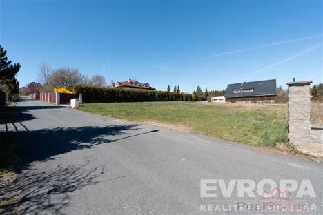 Pr�zdn� pozemek na prodej s asfaltovou p��jezdovou cestou, lemovan� �iv�m plotem, ide�ln� pro stavbu domu v klidn� lokalit�.