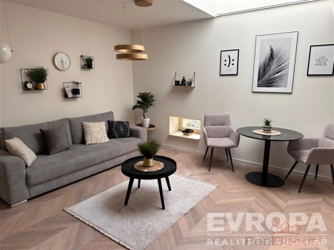 Sv�tl� ob�vac� pokoj se parketovou podlahou, velk� okna, modern� n�bytek, stylov� dekorace, pohodln� sedac� souprava a j�deln� kout.