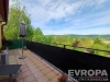 Velk� terasa s dla�bou nab�z� kr�sn� v�hled na okoln� krajinu, ide�ln� pro relaxaci nebo venkovn� posezen�, s modern�m z�bradl�m a zelen� v okol�.