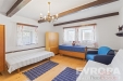 Sv�tl� ob�vac� pokoj s d�ev�nou podlahou, viditeln�mi tr�my a velk�mi okny, za��zen� komfortn�m sedac�m n�bytkem, vytv��� �tulnou atmosf�ru.