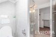 Modern� koupelna s dla�bou, sprchov�m koutem a sv�tl�m keramick�m obkladem.