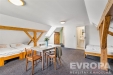 Prostorn� p�dn� pokoj s d�ev�n�mi tr�my, tmav� koberec, dv� postele a p��stup do vlastn� koupelny, ide�ln� pro rekonstrukci.