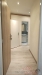 �zk� chodba s d�ev�nou podlahou, modern� osv�tlen�, b�l� st�ny, dve�e vedou do koupelny s dla�bou a umyvadlem, dobr� stav.