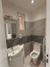 Koupelna s modern� dla�bou, umyvadlovou sk���kou a sv�tle �ed�mi obklady s mal�m oknem poskytuj�c�m p�irozen� sv�tlo.