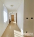 Sv�tl� chodba s d�ev�nou podlahou, modern� dve�e, velk� okna s b�l�mi z�v�sy, minimalistick� design, dob�e osv�tlen�.
