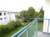 Balkon s modern� dla�bou a modr�m z�bradl�m, s v�hledem na upravenou zahradu obklopenou stromy a reziden�n� budovy v pozad�.