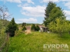 Prostorn� zahrada s udr�ovan�m tr�vn�kem, vzrostl�mi stromy a v�hledem na okoln� krajinu, ide�ln� pro rodinn� aktivity a relaxaci.