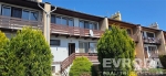 Dvoupodla�n� �adov� d�m s d�ev�n�m balkonem, sv�tlou fas�dou a modern�mi okny. Oplocen� zahrada se vzrostl�mi ke�i.