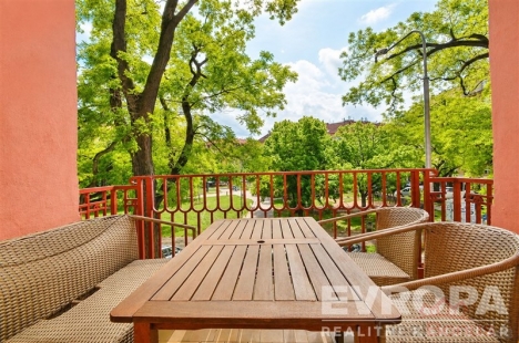 Balkon s d�ev�n�m stolkem, v�hledem na zelen� park, ide�ln� pro relaxaci. Sv�tl� prost�ed� a p��rodn� materi�ly dod�vaj� klidnou atmosf�ru.