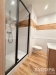 Koupelna s modern� dla�bou imituje d�evo, prostorn� sprchov� kout s �ern�mi detaily a sv�tl� obklady pro elegantn� vzhled.