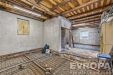 Prostorn� ob�vac� pokoj v rekonstrukci, d�ev�n� stropn� tr�my, betonov� podlaha, p��prava pro modern� povrchy, velk� okna pro p�irozen� sv�tlo.