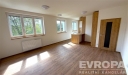 Sv�tl� ob�vac� pokoj s parketovou podlahou, velk�mi okny a modern�m d�ev�n�m oblo�en�m, v nov� rekonstruovan�m byt�.