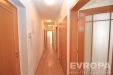 Dlouh� chodba s parketovou podlahou, d�ev�n�mi dve�mi a vestav�n�mi sk��n�mi, vytv��� modern� a praktick� prostor.
