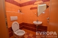 Barevn� toaleta s dla�bou, geometrick� zrcadlo a �sporn� umyvadlo.