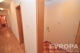 �zk� chodba s parketovou podlahou a dla�bou, b�l� st�ny, d�ev�n� dve�e, modern� interi�r.
