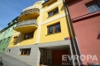 �lut� fas�da bytov�ho domu s d�ev�n�mi okny a modern�m architektonick�m stylem, v klidn� lokalit� na m�rn�m svahu.