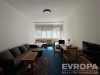 Ob�vac� pokoj s tmav�m kobercem, velk�mi okny a modern�m n�bytkem, vhodn� pro pohodln� bydlen� v rekonstruovan�m stylu.