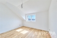 Sv�tl� lo�nice s d�ev�nou podlahou, velk� okna zaji��uj�c� p�irozen� sv�tlo, modern� b�l� st�na pod �ikminou