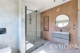 Modern� koupelna s velk�mi okny, dla�bou a d�ev�n�m oblo�en�m. Prostorn� sprchov� kout z �ir�ho skla dod�v� elegantn� vzhled.