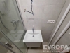 Mal� koupelna s modern� sprchou, dla�bou a b�l�m umyvadlem, nov� zrekonstruovan� interi�r, sv�tl� obklady a �ist� linie.