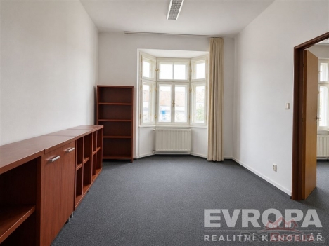 Pracovna s kobercem, vestav�n�mi sk��n�mi a velk�mi okny, kter� poskytuj� dostatek sv�tla, ide�ln� pro modern� kancel��sk� prost�ed�.