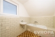 Koupelna s dla�bou, keramick� obklady a vana pod �ikm�m stropem, okno poskytuj�c� p�irozen� sv�tlo, m�rn� podkrovn� styl.