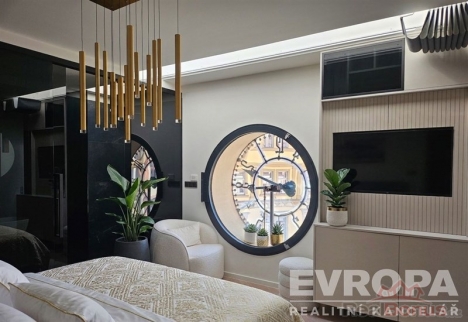 Stylov� lo�nice s modern� dekorac�, kulat� okno, sv�tl� v�malba, vestav�n� sk��n�, d�ev�n� prvky a modern� sv�tidla.