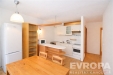 Sv�tl� kuchy� s d�ev�nou podlahou a modern�mi spot�ebi�i, otev�en� prostor propojen� s j�delnou, sv�tl� st�ny a vestav�n� sk��n�.